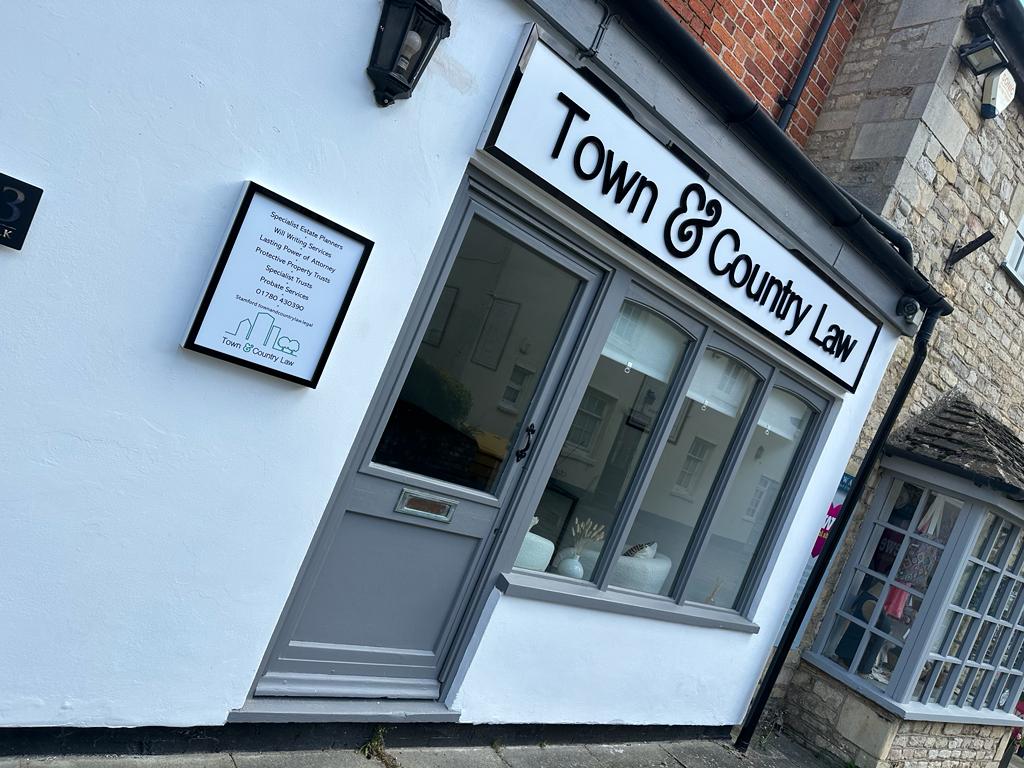 The Town & Country Law shopfront, painted black wordmark on white render under a Georgian-stone surround, on Stamford Walk